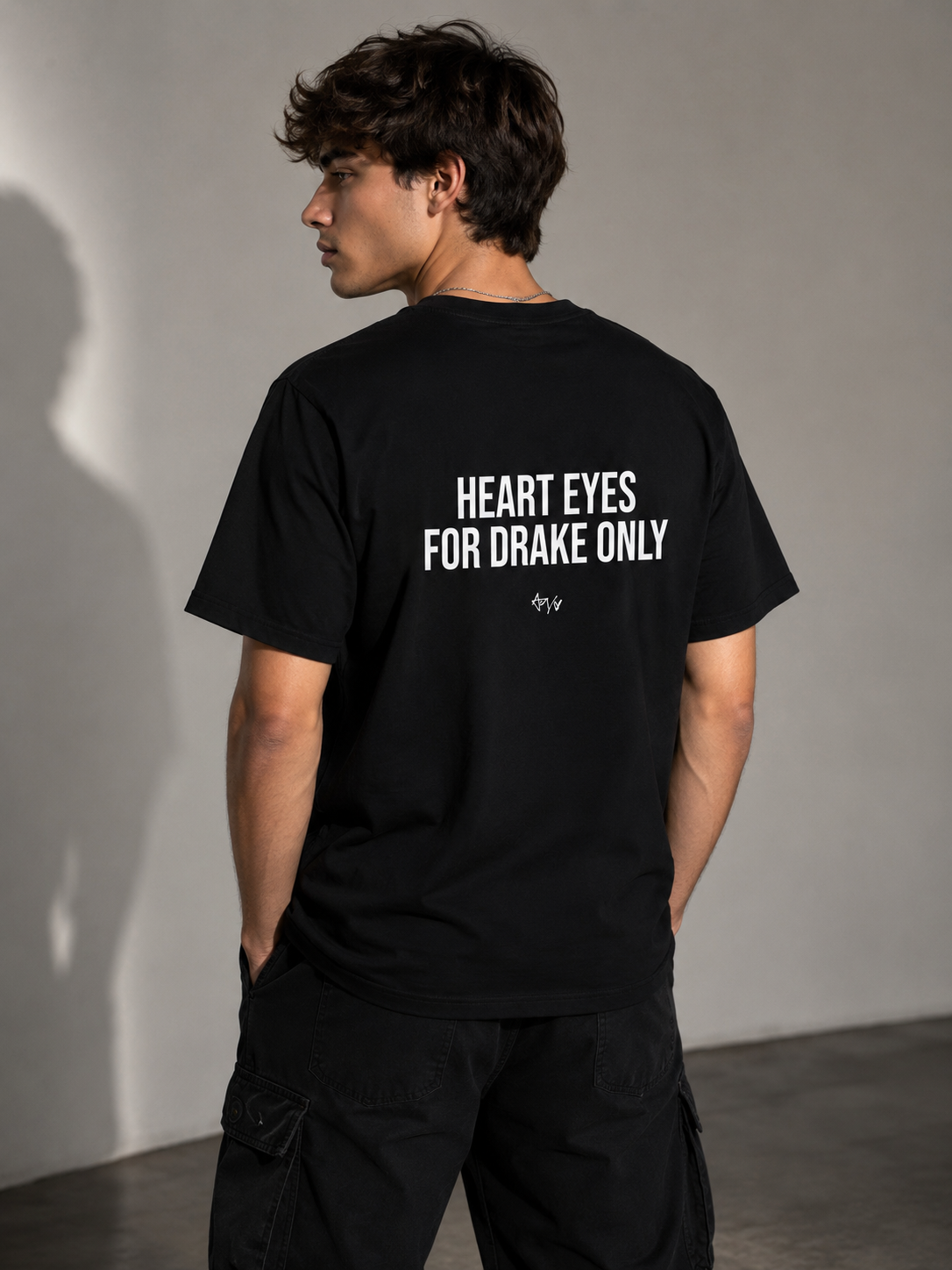 Person wearing a black t-shirt with text on the back, standing against a plain background