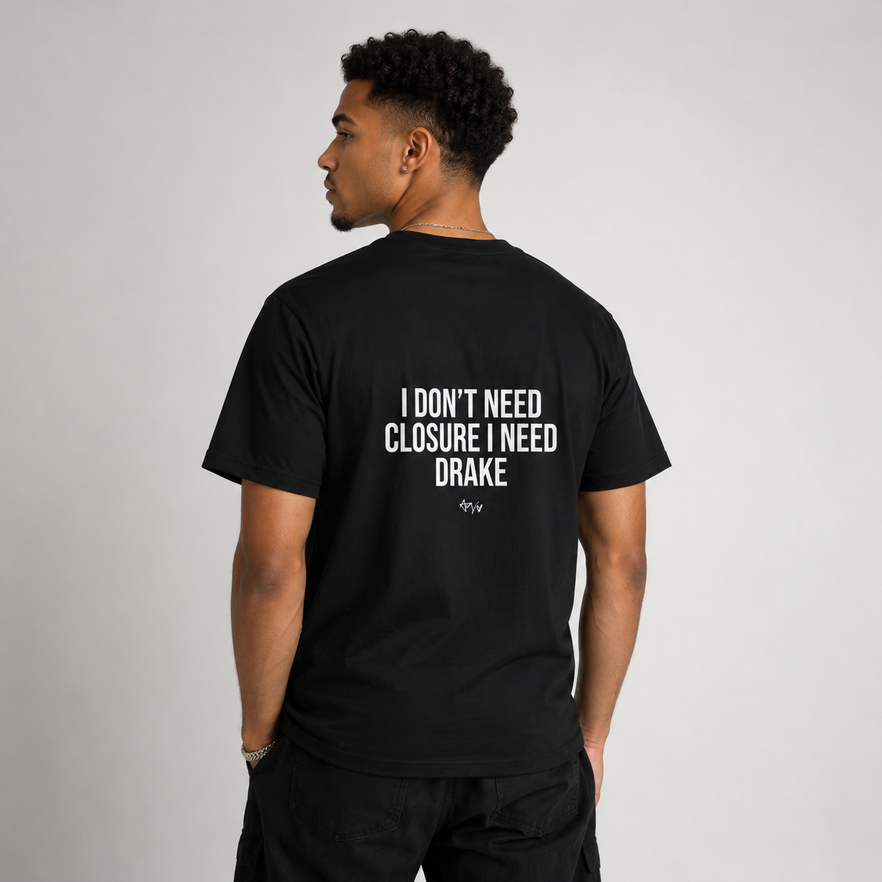 Person wearing a black t-shirt with text on the back, standing against a plain background